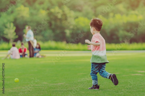 Kid enjoy to playing with little ball on green field © JinnaritT