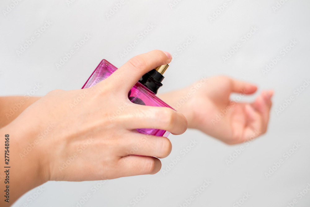 young woman is spraying perfume on his wrist.