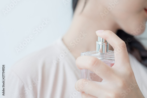 woman is spraying perfume at the neck.