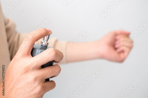 Men are spraying perfume on his wrist.