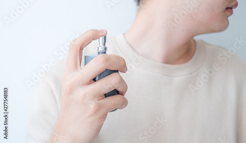 Men are spraying perfume at his neck.