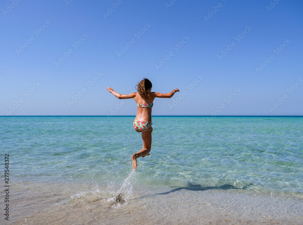 Slim and athletic girl in a colourful bikini jumping into the crystal clear water of a beautiful beach -vacation-fitness-wellness Slim and athletic girl in a colourful bikini jumping into the crystal clear water of a beautiful beach -vacation-fitness-wellness