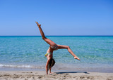 Slim and athletic girl doing yoga, pose, calisthenics, fitness training on a wonderful beach with crystal clear water -vacation-fitness-wellness
