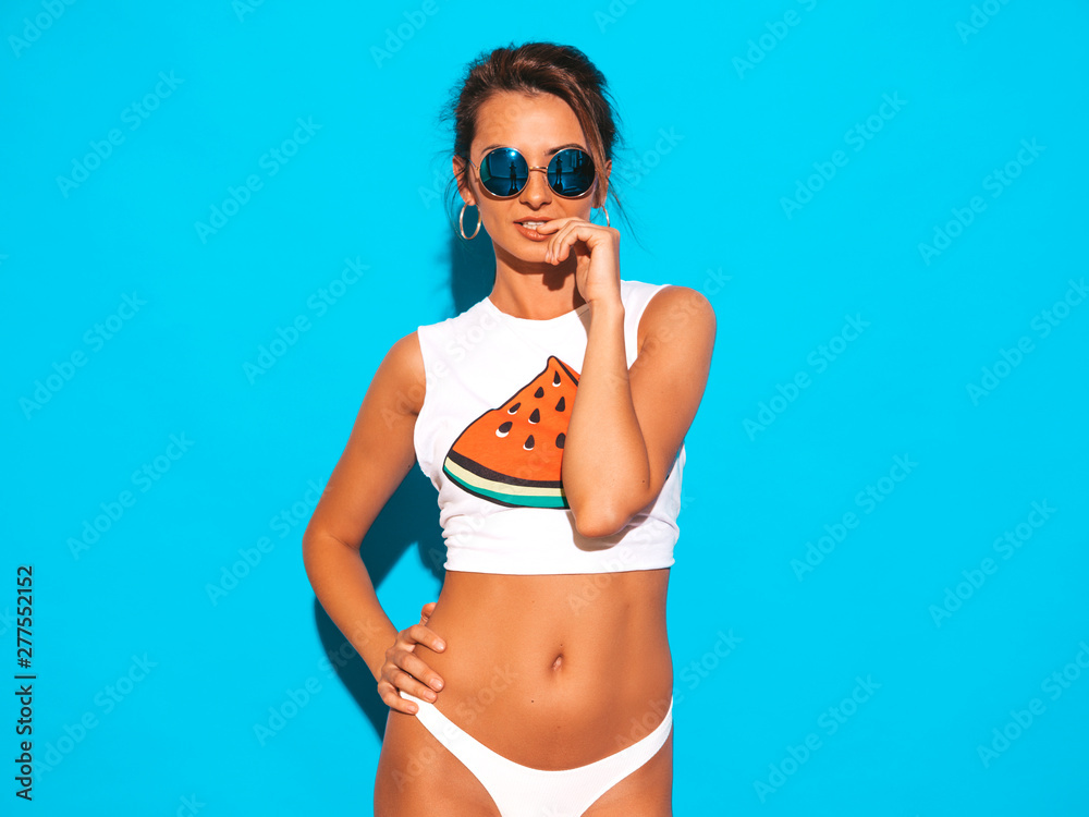 Portrait of young beautiful sexy smiling hipster woman in white summer underpants and topic.Trendy girl in sunglasses. Positive female going crazy.Funny model isolated on blue Portrait of young beautiful sexy smiling hipster woman in white summer underpants and topic.Trendy girl in sunglasses. Positive female going crazy.Funny model isolated on blue