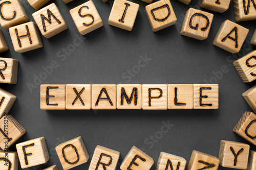 Slika na platnu word example composed of wooden cubes with letters, something typical represent