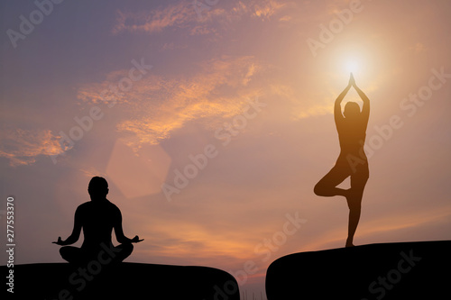 The silhouette of a woman practicing yoga on a rock during a beautiful sunset
