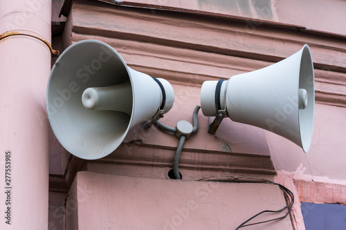 two loudspeakers on a pink wall