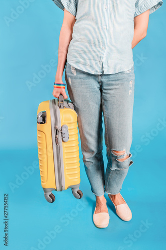 Girl with lgbt bracelet carries a suitcase to the plane. The concept of travel for gays and gender immigration