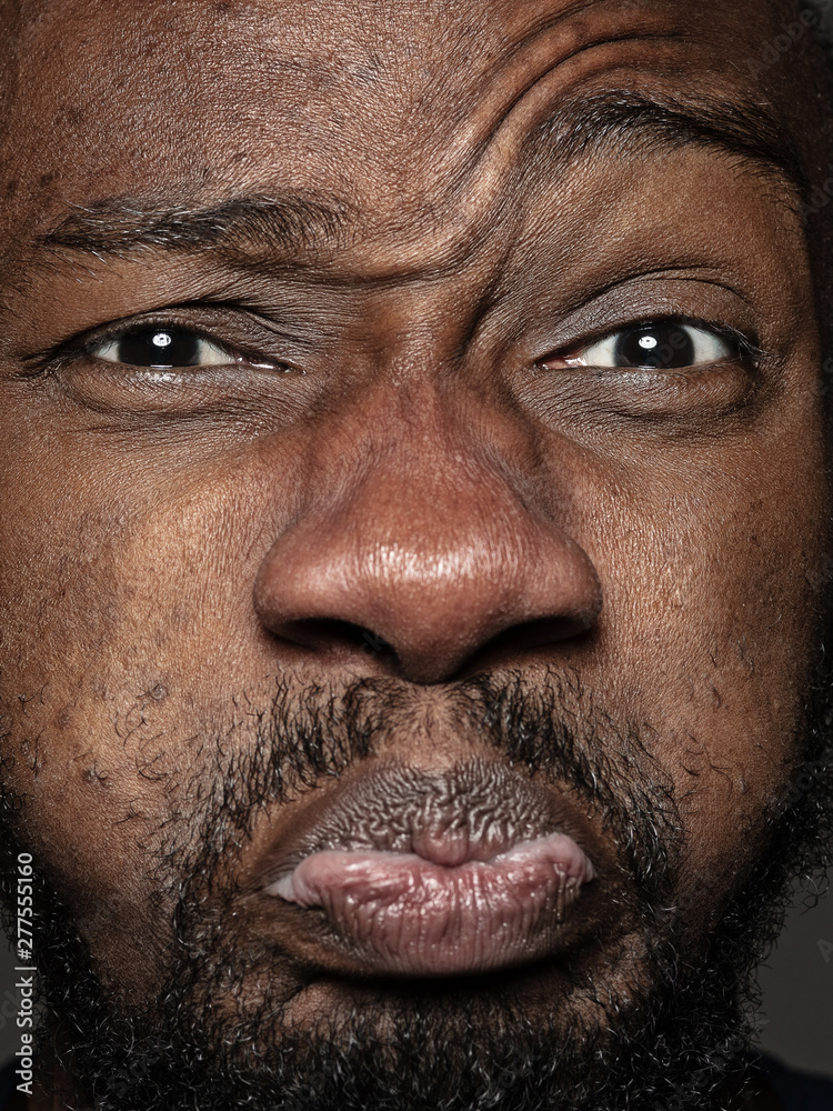 Obraz premium Close up portrait of young and emotional african-american man. Highly detail photoshot of male model with well-kept skin and bright facial expression. Concept of human emotions. Happy grimaces.