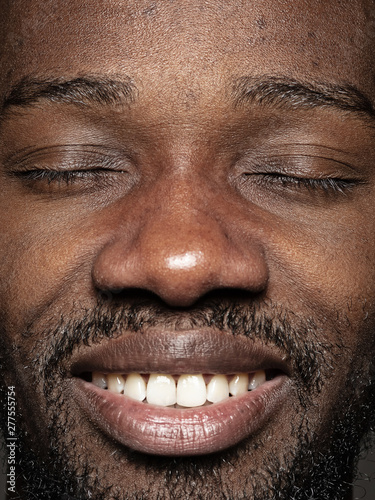 Close up portrait of young and emotional african-american man. Highly detail photoshot of male model with well-kept skin and bright facial expression. Concept of human emotions. Happy smiling and calm