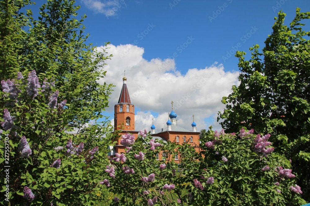Spring landscape with a blooming lilac and church in the city of Kanash