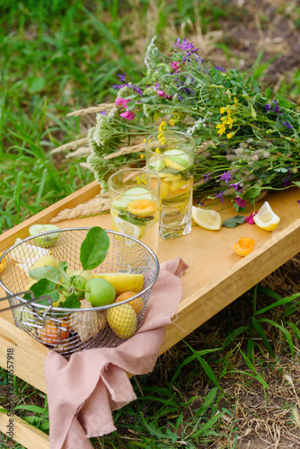 Summer lemonade with lemon, lime, ginger, with wildflowers on the table. Cooling drinks