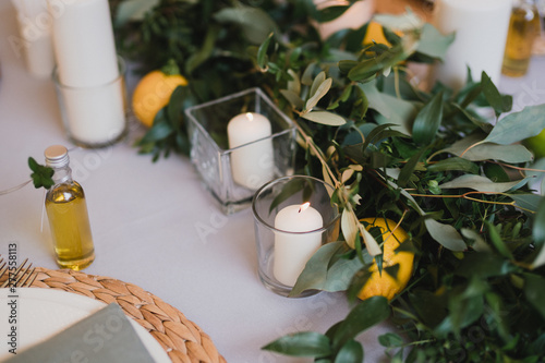 Coziness and style. Modern event design. Table setting at wedding reception. Floral compositions with beautiful flowers and greenery, candles, laying and plates on decorated table.