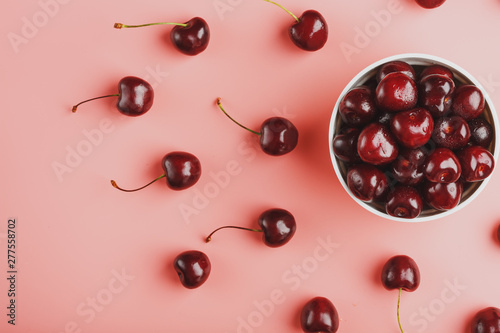 Cherry berry on a pink background in a white cup, top view.