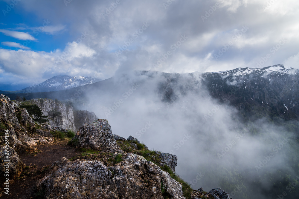 Montenegro, Misty atmosphere and extremely fast changing weather on summit of mount curevac at the edge of tara river canyon inside durmitor national park nature landscape near zabljak