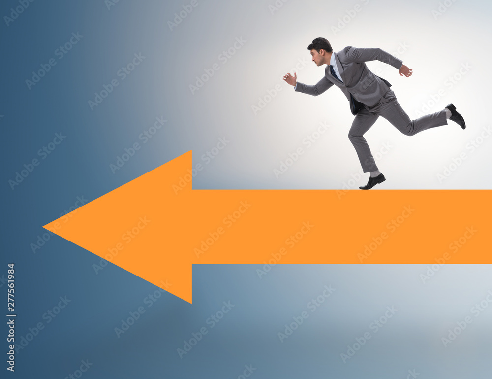 Businessman walking on arrow in business concept Businessman walking on arrow in business concept
