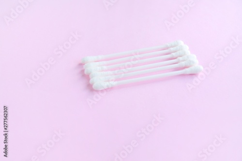 Row of white clean cotton swabs with selective focus on pink neutral background with empty space for text. Personal hygienic cotton buds for daily routine. Soft cotton ear sticks. Healthcare tools 