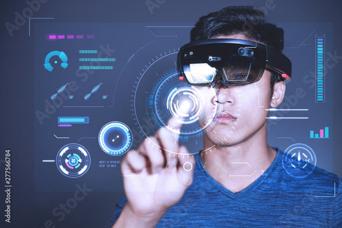 The Asian young man with glasses of virtual reality. Experience VR hololens headset in studio with advanced technology.
