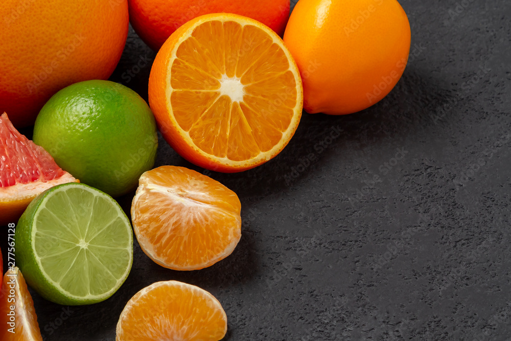 group of whole and sliced citrus fruits - tangerines, lemons, limes, oranges, grapefruits on the surface of the dark table - image with copy space group of whole and sliced citrus fruits - tangerines, lemons, limes, oranges, grapefruits on the surface of the dark table - image with copy space