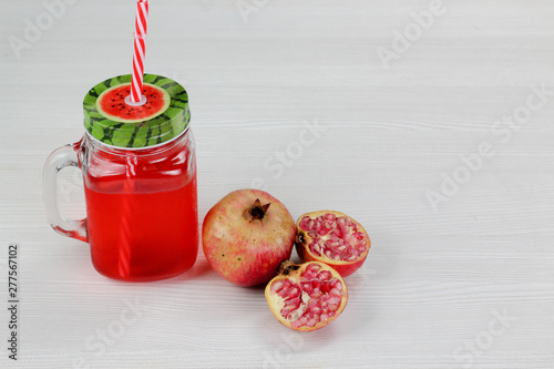 pomegranate juice in vintage Mason jar with red straw, red fruit.