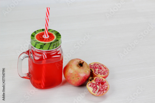 pomegranate juice in vintage Mason jar with red straw, red fruit.
