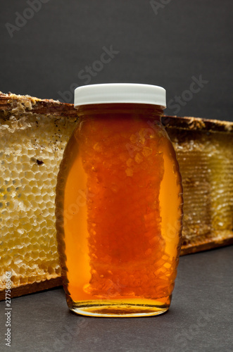 Jar of honey with part of bee have.