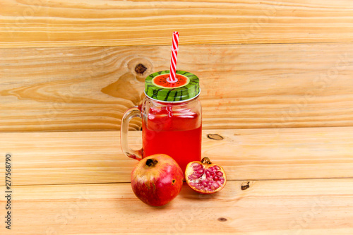 pomegranate juice in vintage Mason jar with red straw, red fruit.