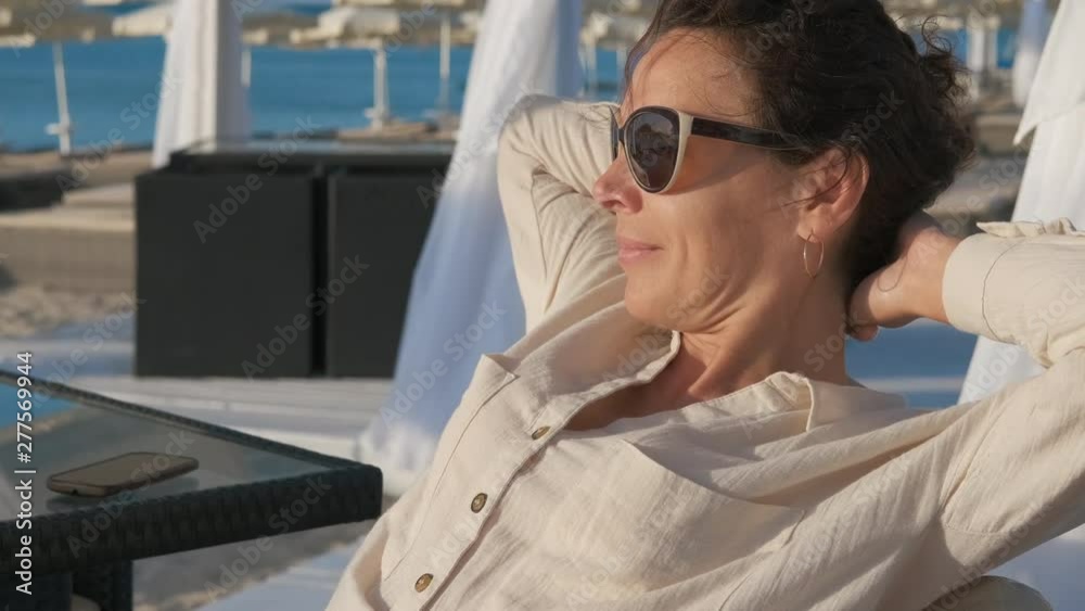 A woman on a deserted beach. Pretty woman is enjoying the sunrise in an empty cafe on the beach. A woman on a deserted beach. Pretty woman is enjoying the sunrise in an empty cafe on the beach.