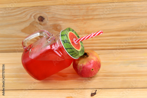 pomegranate juice in vintage Mason jar with red straw, red fruit.