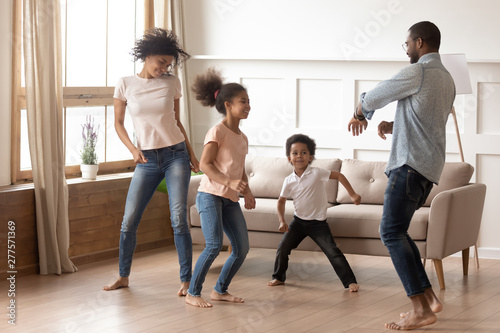 Fototapeta Naklejka Na Ścianę i Meble -  Happy funny active african family of four dancing at home