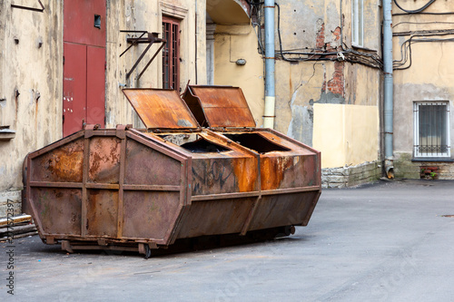 rusty dumpster in the courtyard of a residential building. dump in the center of St. Petersburg, Russia 2019