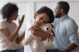 Sad african child boy embrace toy upset by parents arguing