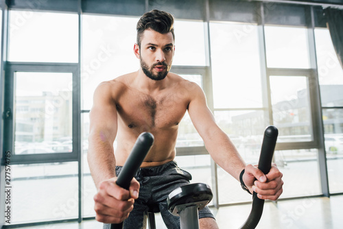 handsome shirtless sportsman training on elliptical machine at gym