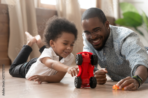 Cute little african kid son playing toy cars with dad photo