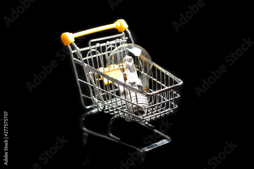 Close-up of shopping carts on black background.Trolley, Sale concept. Isolated over black background in a cart lies a electric lamp.