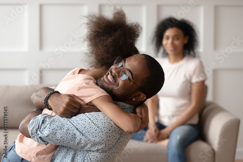 Quadro em tela Happy african american dad embracing daughter cuddling at home