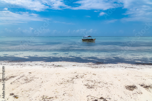 Zanzibar in Tanzania, beautiful beach with white sand, and a typical fishing boat