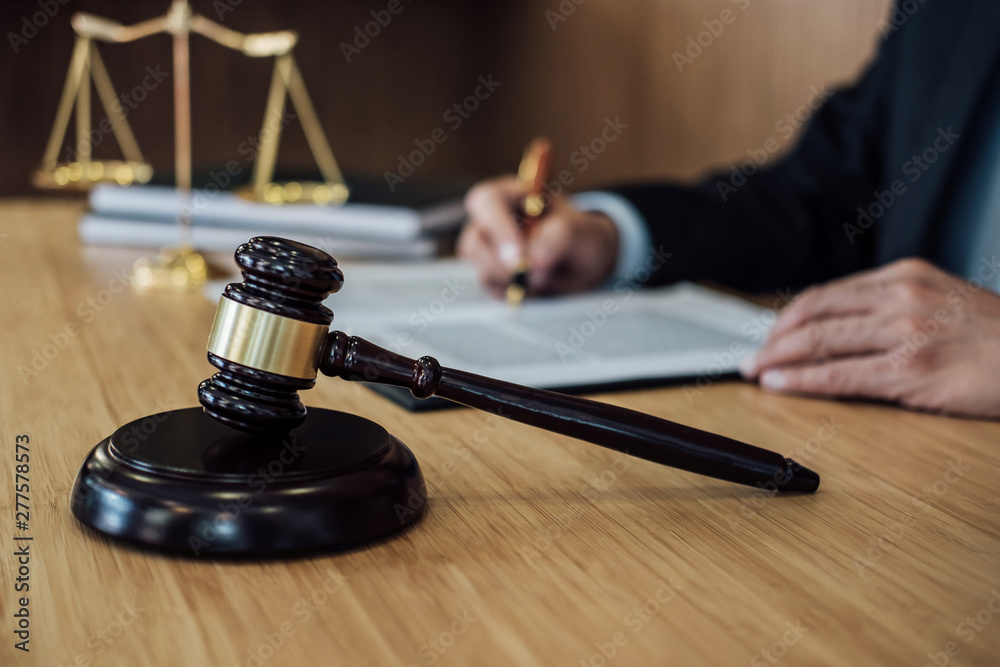 Gavel on wooden table and Lawyer or Judge working with agreement in Courtroom theme, Justice and Law concept Gavel on wooden table and Lawyer or Judge working with agreement in Courtroom theme, Justice and Law concept