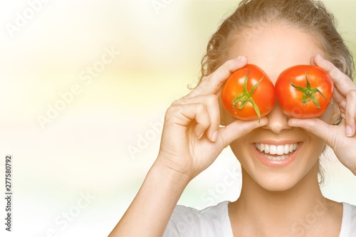 Beautiful laughing woman holding two ripe tomatoes