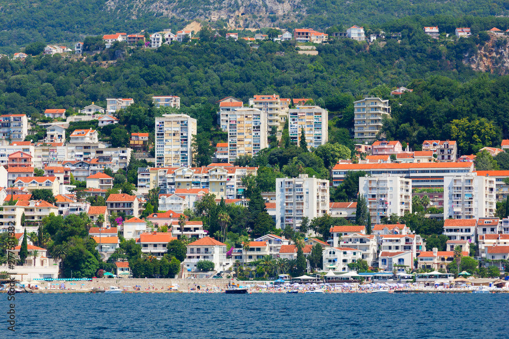 The city with roofs of houses of orange color at the coast of the Mediterranean sea. Architecture of Montenegro
