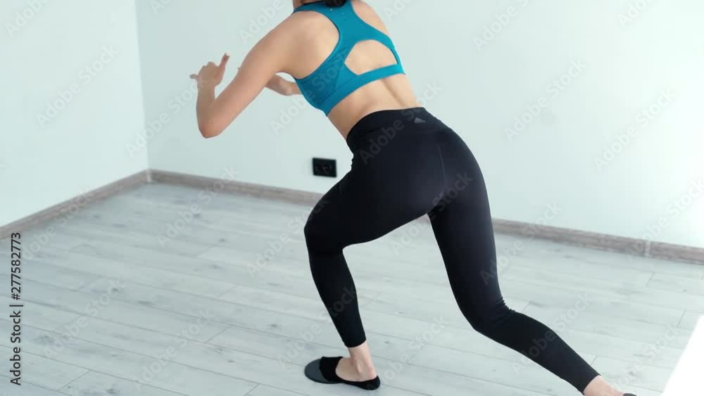 Young sexy woman in sport wear doing squats in light fitness club in slow motion. Active young woman exercising at the gym Young sexy woman in sport wear doing squats in light fitness club in slow motion. Active young woman exercising at the gym