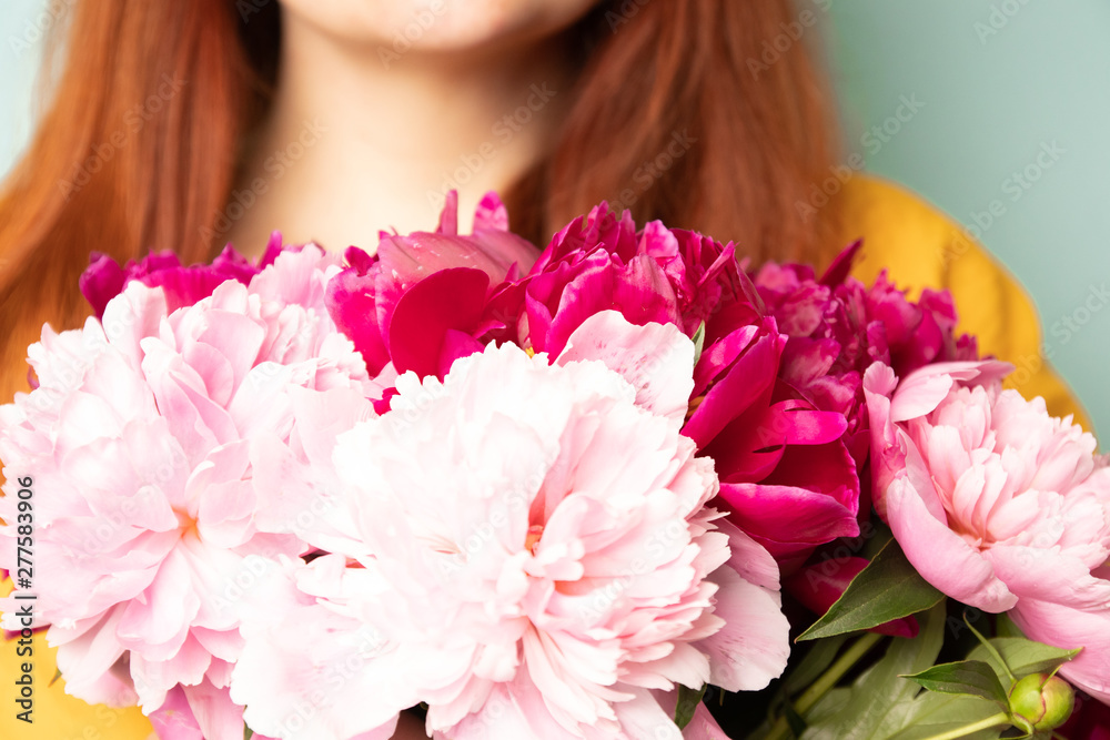 Happy girl with a bouquet of peonies on light blue background Happy girl with a bouquet of peonies on light blue background