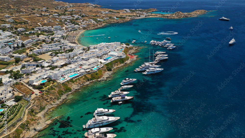 Aerial panoramic photo of famous turquoise clear sea celebrity sandy beach and bay of Psarou with yachts and sail boats in iconic island of Mykonos, Cyclades, Greece