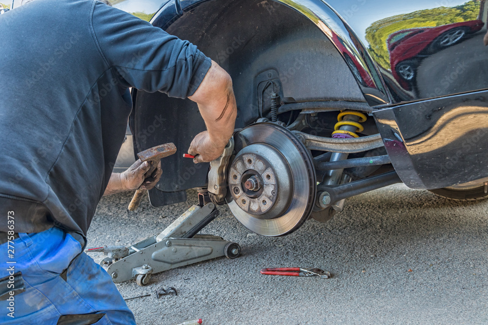 Fototapeta premium A man changes brake pads on a car.