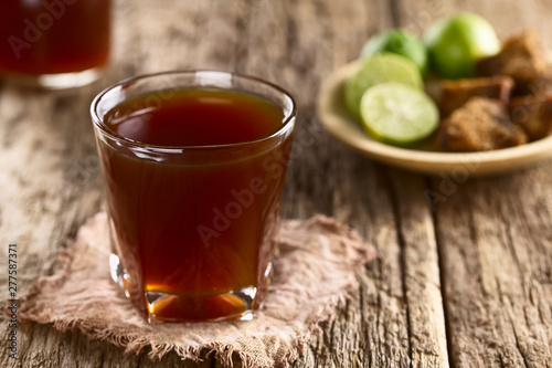 Fresh homemade Aguapanela, Agua de Panela or Aguadulce, a popular Latin American sweet drink made of panela unrefined whole cane sugar boiled in water (Selective Focus on the front of the glass rim) photo