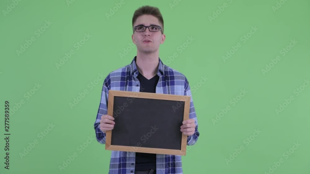 Happy young hipster man thinking while holding blackboard Happy young hipster man thinking while holding blackboard