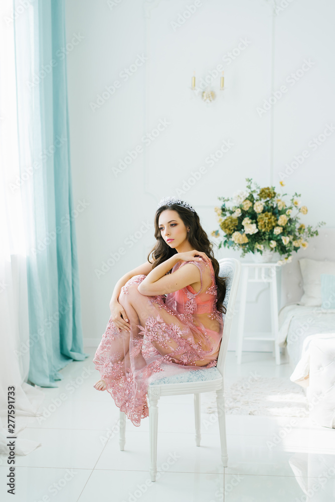 Portrait of sexy woman with soft skin, dressed in a pink lace dressing gown lingerie sexy while remaining in the background of the boudoir. Beautiful girl sitting on a white chair Portrait of sexy woman with soft skin, dressed in a pink lace dressing gown lingerie sexy while remaining in the background of the boudoir. Beautiful girl sitting on a white chair