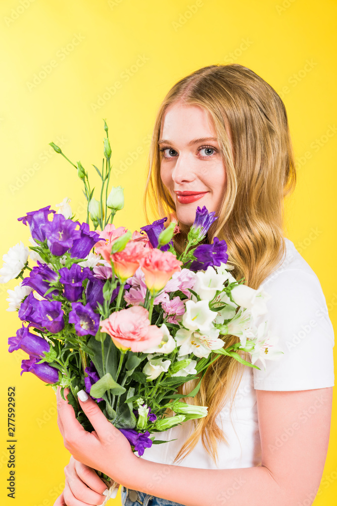 beautiful blonde girl with flowers looking at camera On yellow