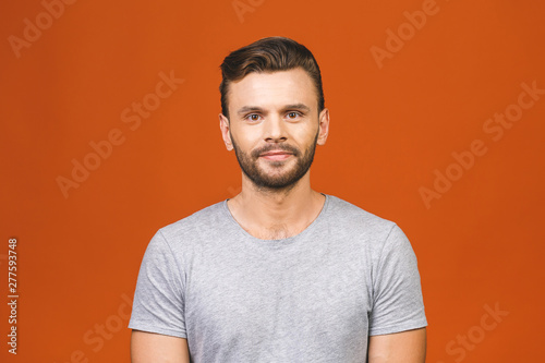 Casually handsome. Confident young handsome man in jeans shirt smiling while standing against orange background.