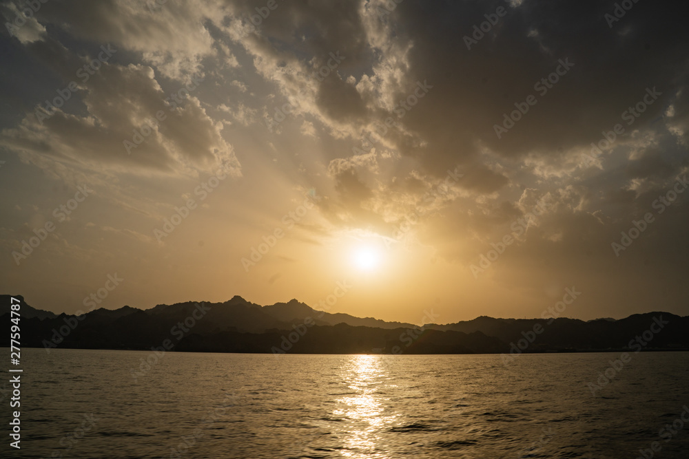 Sunset view of Muscat along the coast from a boat on the ocean Sunset view of Muscat along the coast from a boat on the ocean
